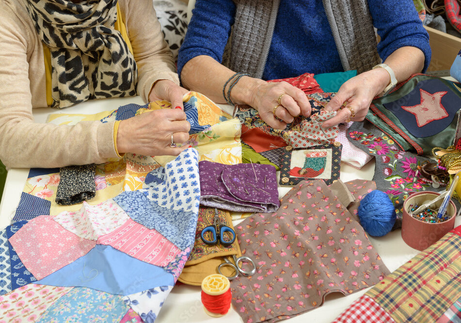 A photo showing the hands of two older adults working together on a quilting project